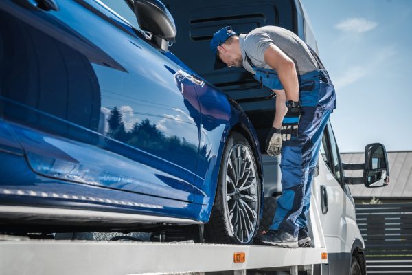 Car Repossession Worker Securing Vehicle on His Towing Truck. Vehicle Financing and Repo Company.