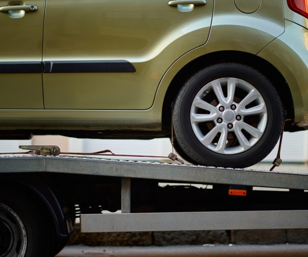 Car fixed on tow truck with metal winch and hooks. Vehicle problem on road. Closeup cropped image.